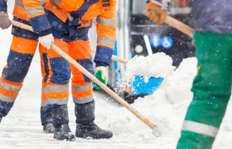 Snowplow clearing a park pathway in a city during winter storm